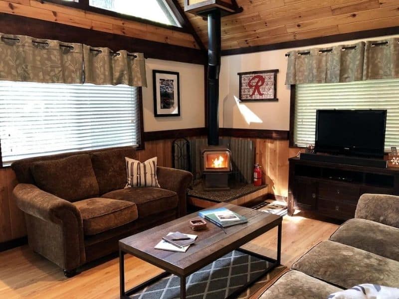 Rustic cabin living area with wood burning fireplace and couches
