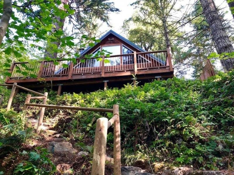 Looking up a walkway to a wood cabin near Mt Rainier with a large deck surrounded by trees