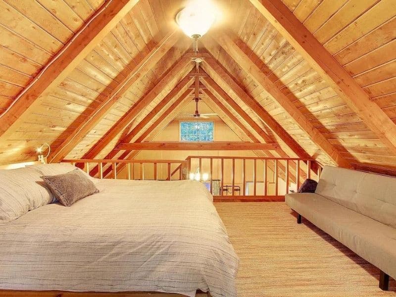 Loft cabin bedroom with large bed and vaulted wood ceilings