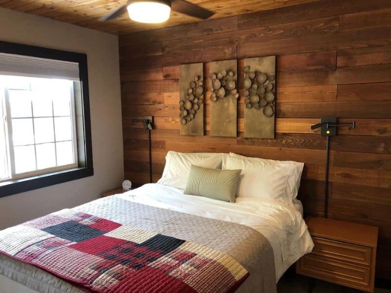 Small cabin bedroom with wood panel accent wall and quilted duvet