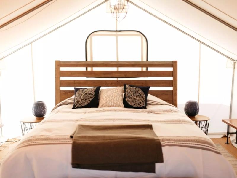 Interior of glamping tent at BaseCamp 39 near Zion with wood headboard and decorative throw pillows