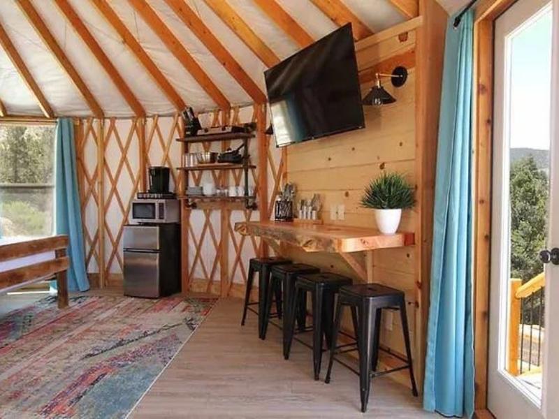Interior of yurt at East Zion Glamping Resort with breakfast bar with barstools, TV, microwave and mini fridge