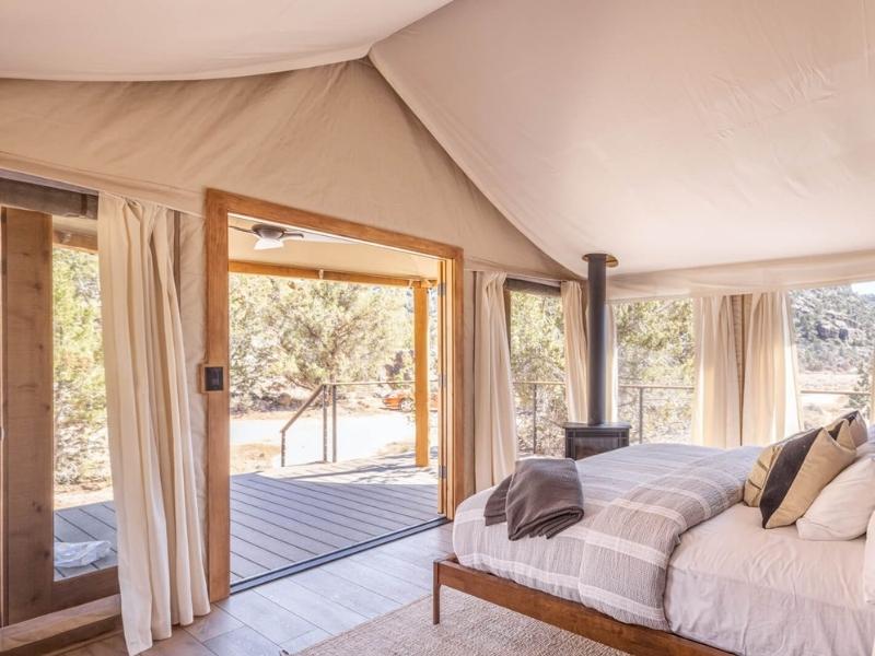 Interior of luxury glamping tent at Open Sky Glamping Zion with plush king size bed and wood burning fireplace