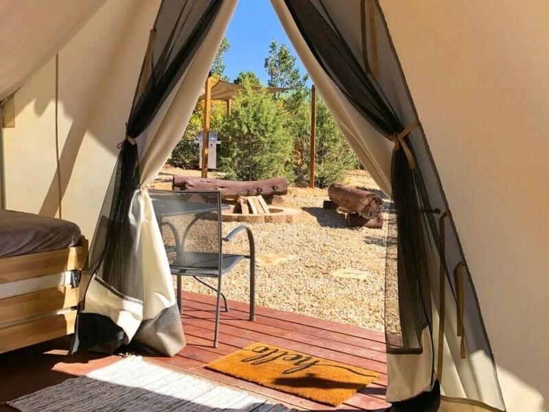 View from glamping tent at Zion Ponderosa Ranch with wooden deck, chairs, and picnic table