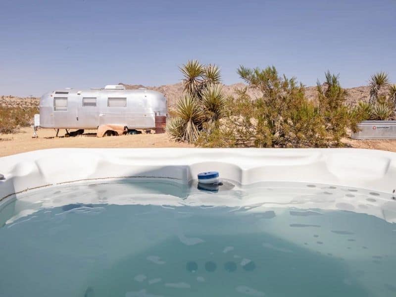 Hot tub and Airstream trailer at Streamliner Joshua Tree Airbnb