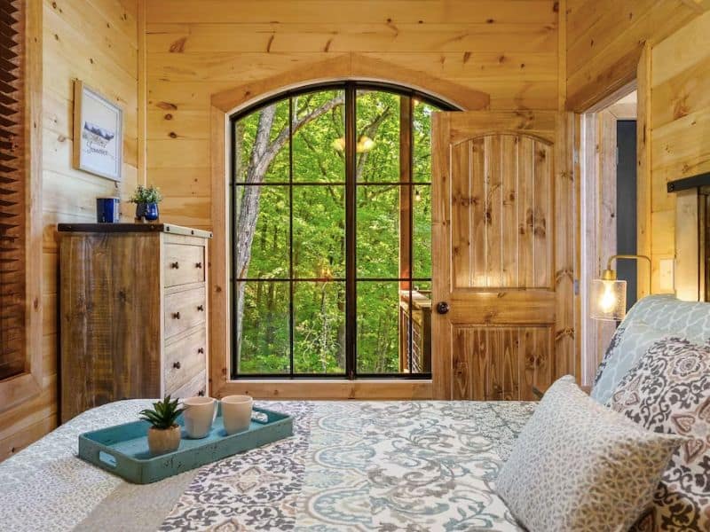 Bedroom of Pigeon Forge cottage, with floor to ceiling pine paneling and quilted bedding. Forest view.