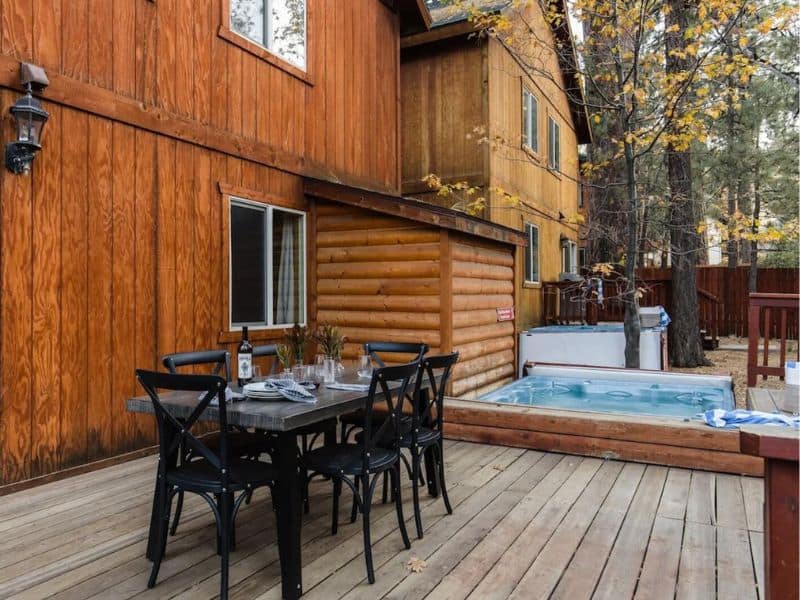 Outdoor deck with table and hot tub at holiday rental in Big Bear CA