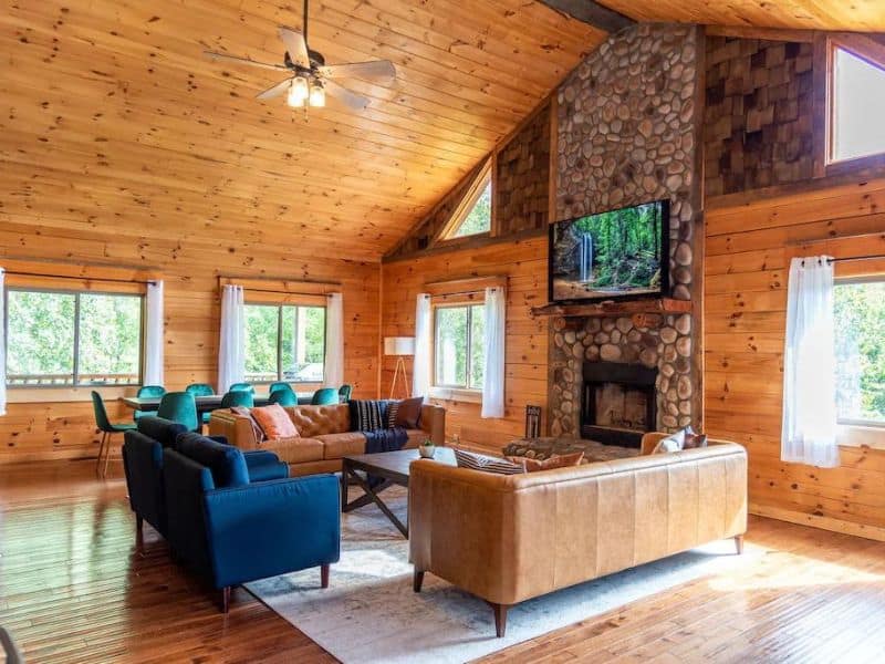 Rustic luxury living area in a upscale wood cabin with stone fireplace and large TV