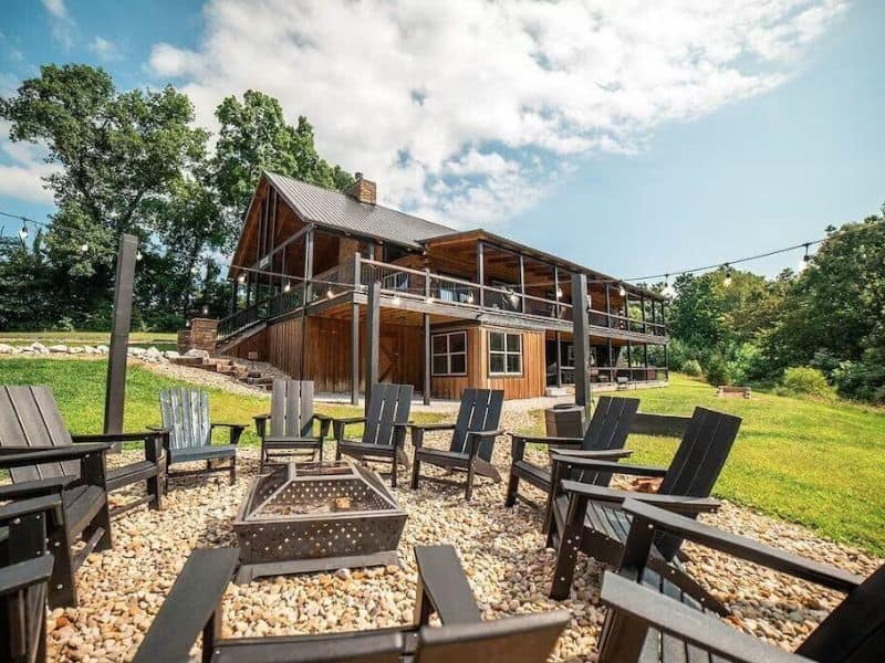 Modern wood cabin with outdoor fire pit surrounded by Adirondack chairs