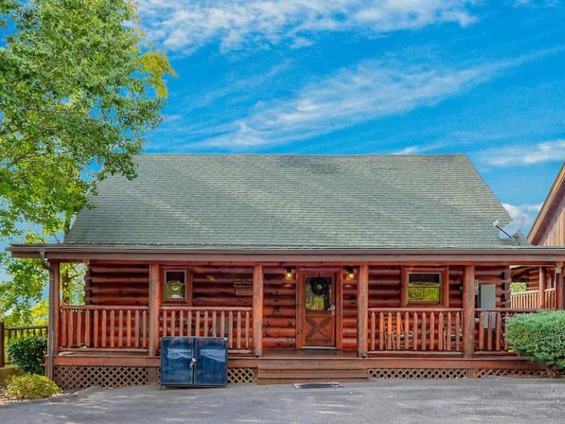 Vacation rental in Pigeon Forge with log cabin construction, porch, and surrounding trees.
