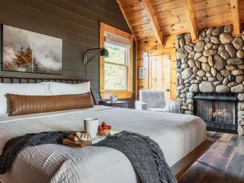 Bedroom with river stone fireplace, modern accents, and angled wood paneled ceiling, in Pigeon Forge rental property.