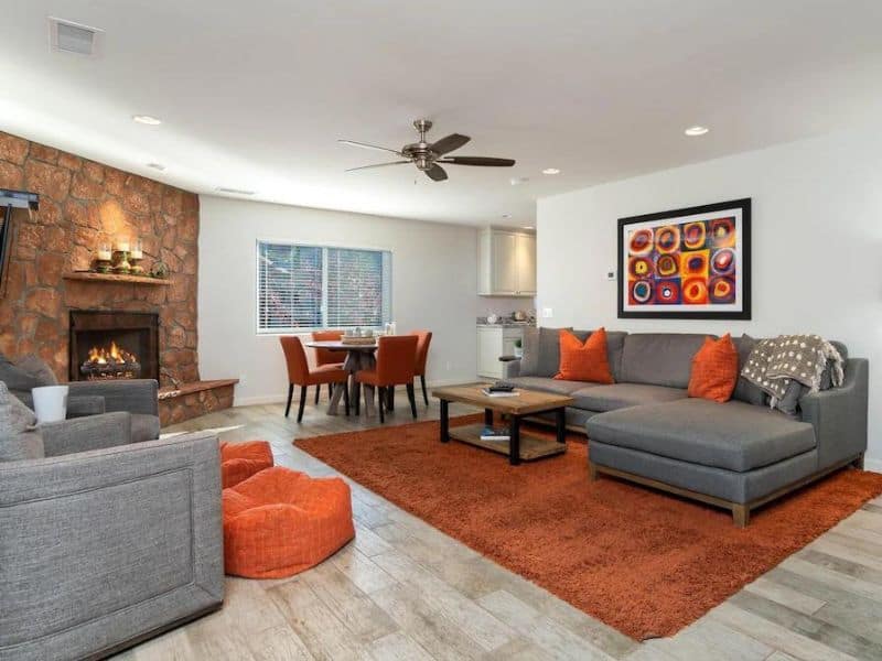 Living area in Sedona Vrbo with fireplace, grey sectional couch, and orange pops of color