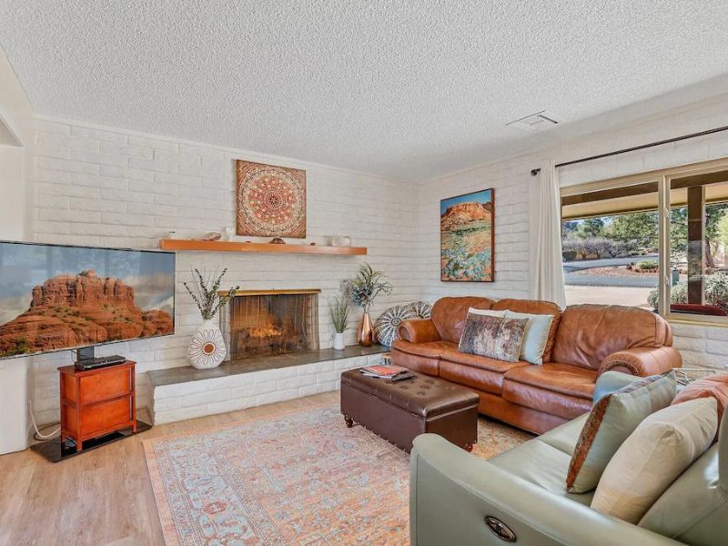Living room of Sedona vacation home with fireplace, whitewashed walls, and colorful bohemian accents.