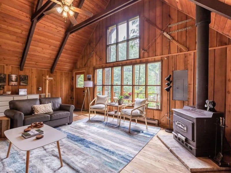 Large airy living area in A-frame cabin in Packwood with area rug and wood-burning fireplace. Part of a guide to the best Mt. Rainier cabin rentals