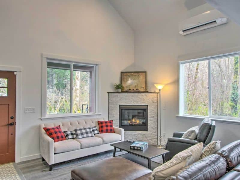 Modern cabin interior living room with fireplace, comfy couches, and plaid throw pillows
