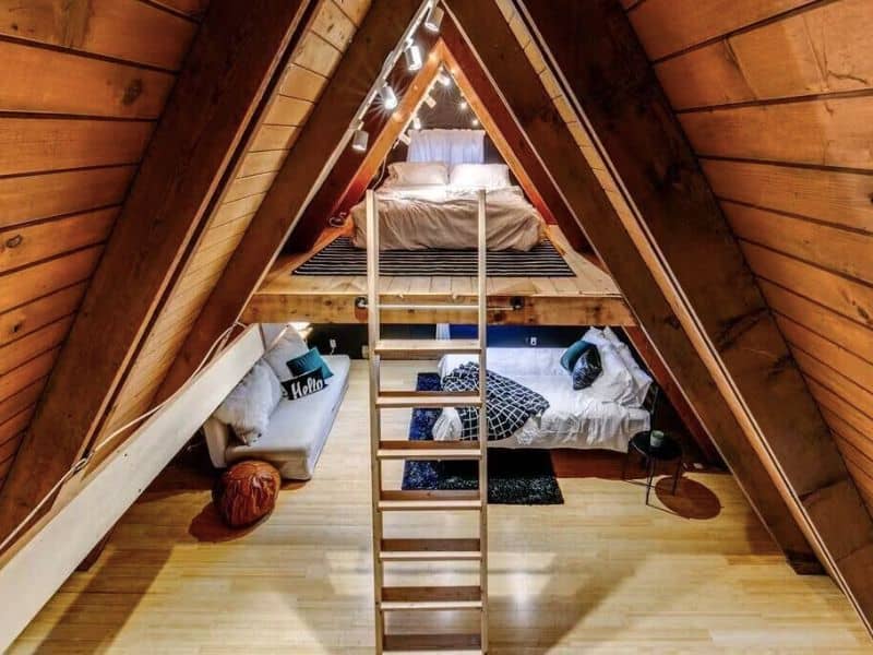 Larger bedroom with ladder leading up to small loft bed in A-frame cabin rental in Packwood, WA