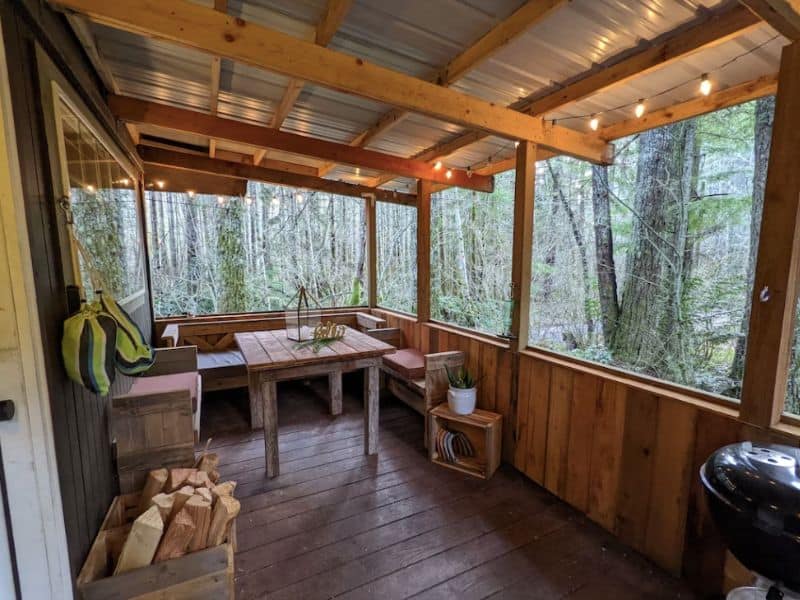 Charming covered wood deck with seating and fairy lights in cabin near Mt Rainier