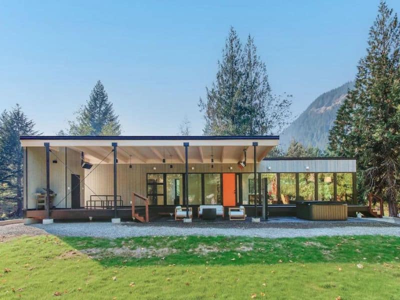 Exterior of modern cabin with sleek lines and covered deck with hot tub - part of a guide to the best Mt. Rainier cabin rentals