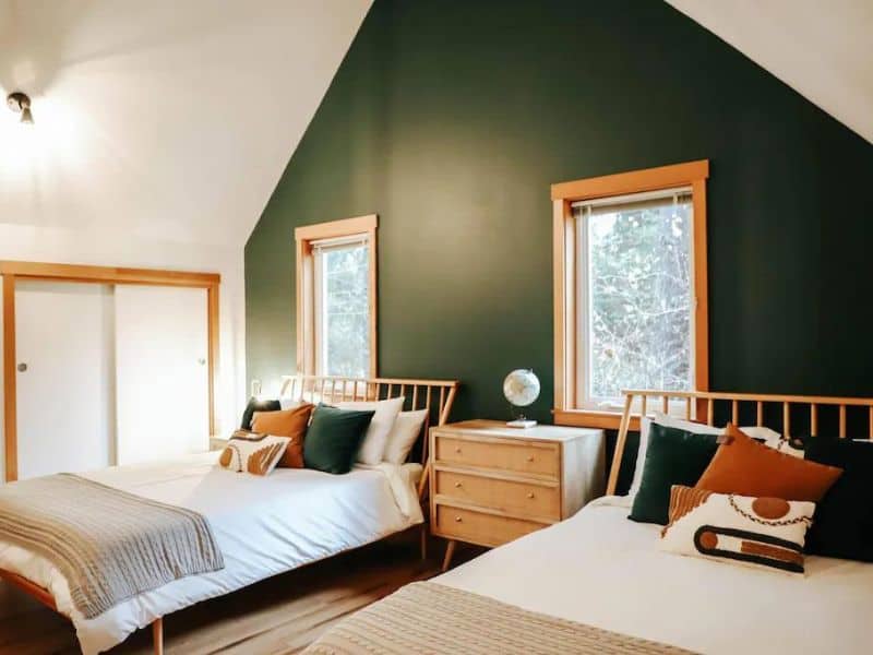 Twin bedroom in A-frame cabin with pine green accent wall