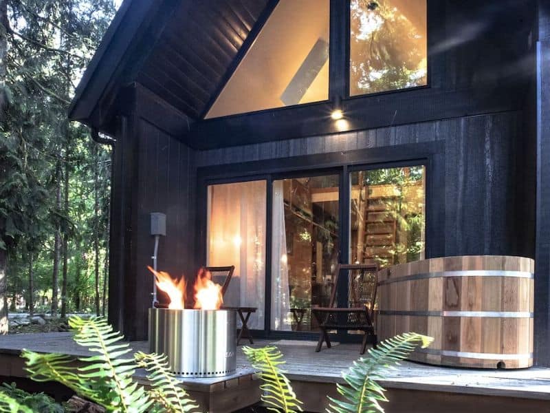 Modern black A-frame cabin rental near Mount Rainier with gas fire pit and outdoor soaking tub on the deck