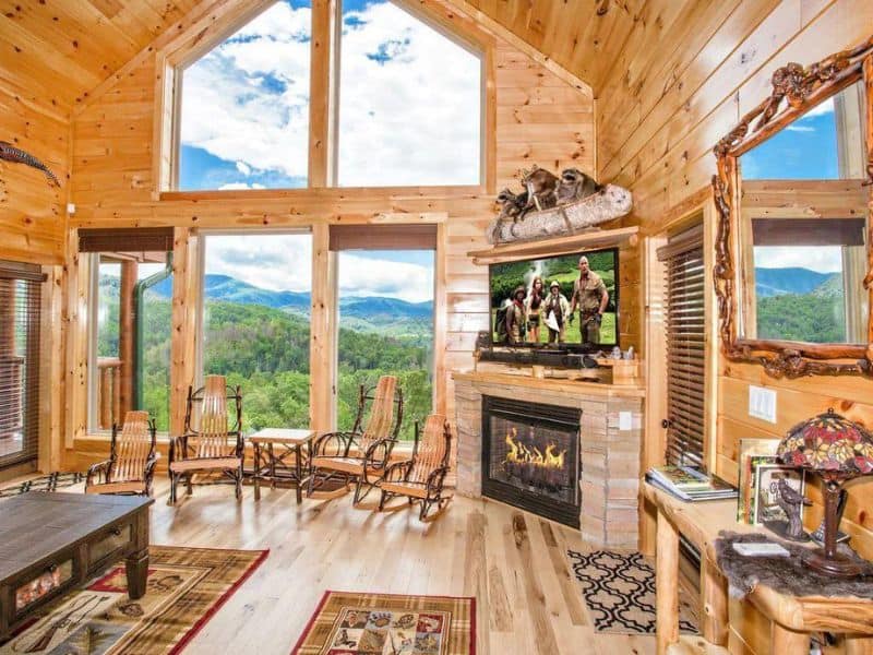 Living room with fireplace, vaulted ceilings and large floor-to-ceiling windows overlooking the Great Smoky Mountains