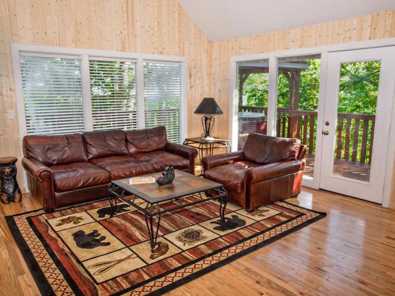Modern rustic living area in Chalet Village cabin rental near Gatlinburg with rug, coffee table, and leather couches