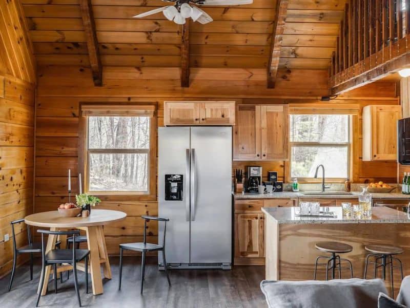 Modern rustic kitchen in cabin with stainless steel refrigerator and small dining area