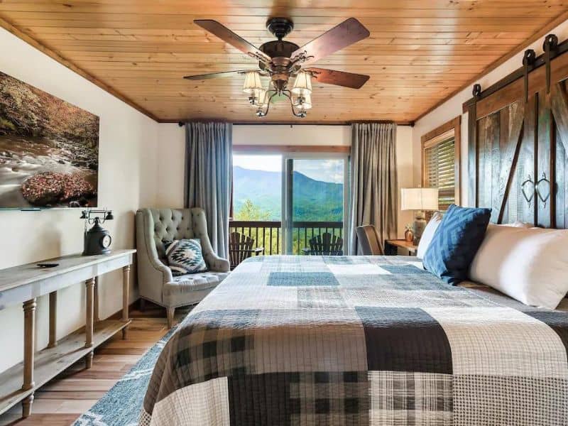 Guest room with quilted bed, ceiling fan, and direct deck access in Gatlinburg cabin rental