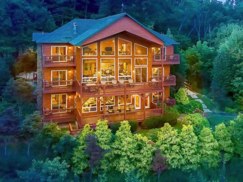 Exterior of large multi-story wood cabin in Gatlinburg with trees in the foreground - part of a curated guide to the best pet-friendly cabins in Gatlinburg