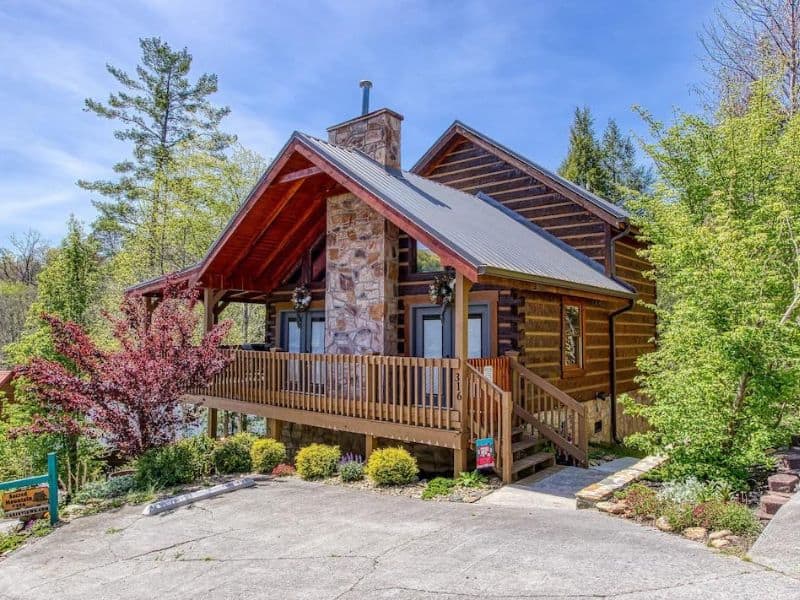 Exterior of wood cabin with stone chimney and covered wooden deck in Gatlinburg - part of a curated guide to the best pet-friendly Gatlinburg cabins