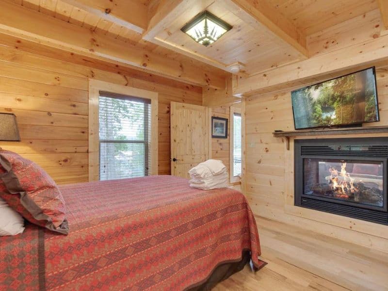 Bedroom with fireplace and TV in wood cabin rental in Gatlinburg
