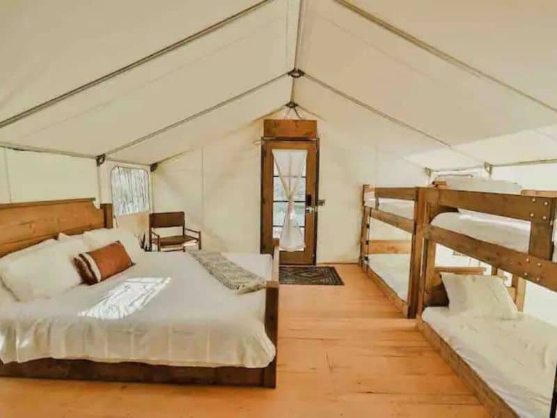 Interior of large canvas family glamping tent at Cave Lakes Canyon Ranch near Zion National Park with king bed and two twin bunk beds