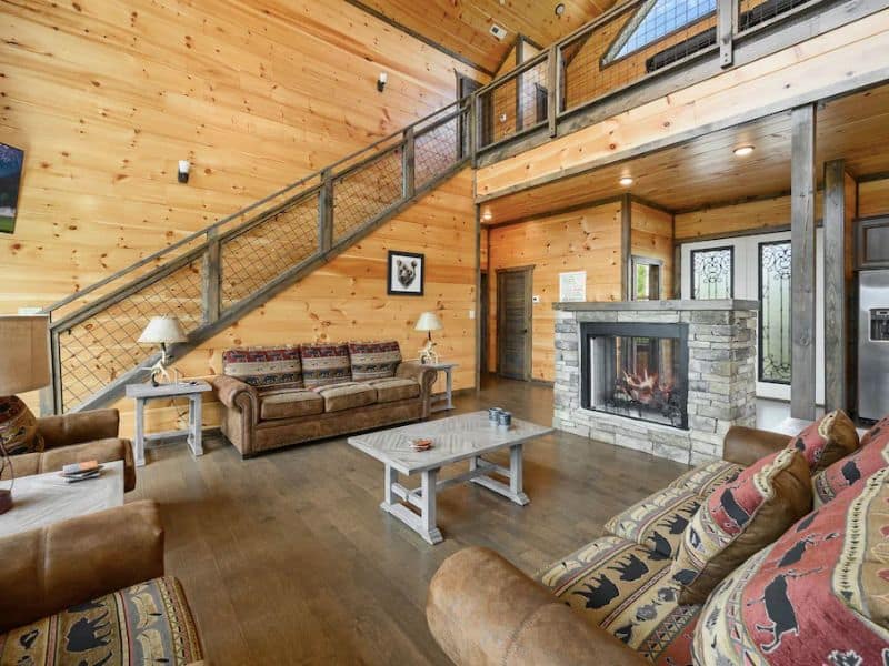 Open plan living area with couches and fireplace in cabin rental in Gatlinburg