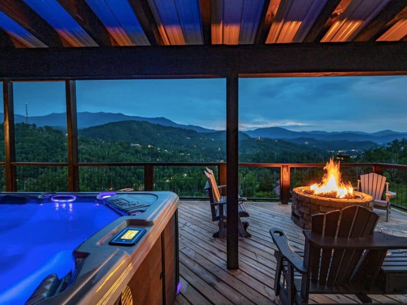 Large covered deck with hot tub and fire pit offering views of the Great Smoky Mountains - part of a guide to the best large cabin rentals in Gatlinburg, TN