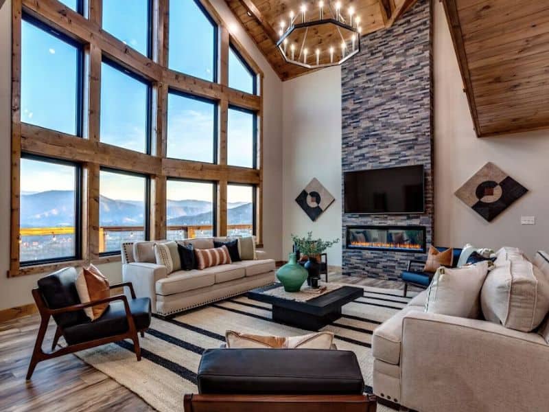 Modern living area with fireplace, TV, and floor-to-ceiling windows at luxury rental property in Gatlinburg