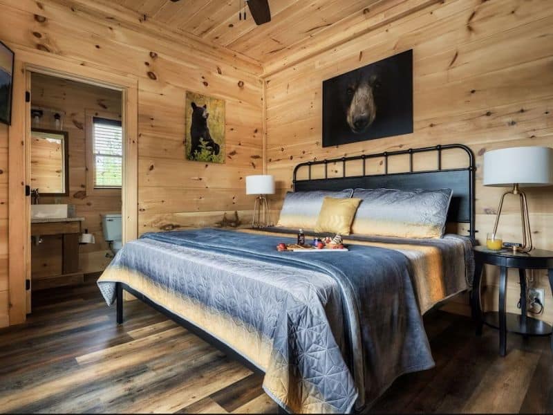 Chic bedroom in large cabin rental in Gatlinburg TN with wood accents and a blue and yellow duvet.