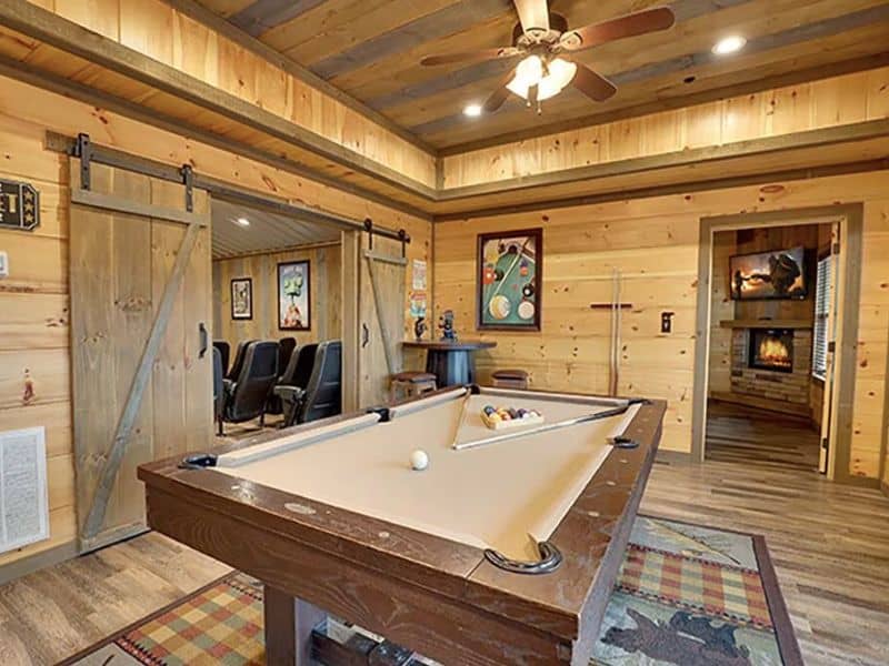 Game room with pool table with barn doors opening into an in-home theater room at a large Gatlinburg cabin rental
