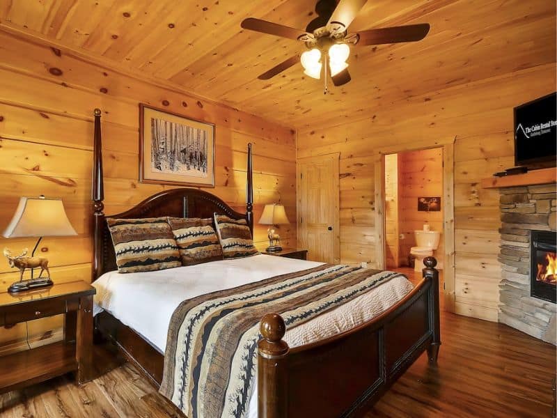 Bedroom in Gatlinburg cabin rental with ensuite bathroom and wood finishes.