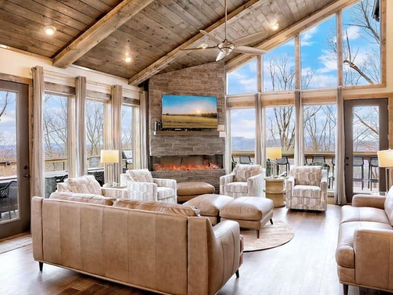 Modern open concept living area at upscale Gatlinburg cabin with leather couch, plush seats, and sleek fireplace