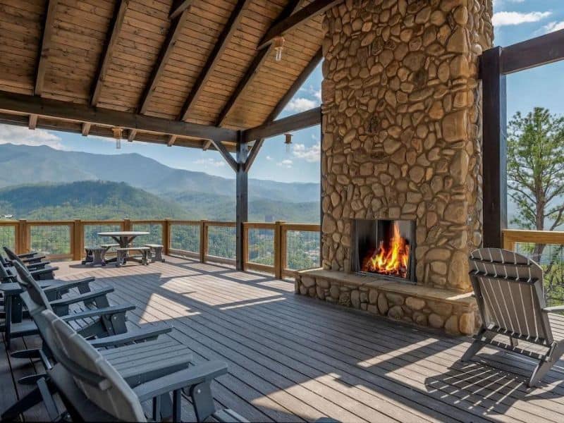 Outdoor deck overlooking the Great Smoky Mountains with large natural stone fireplace.
