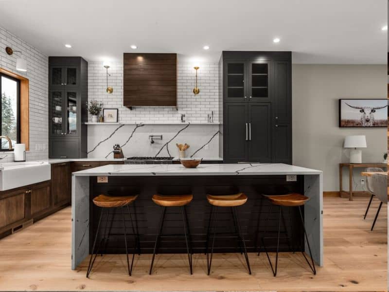 A modern kitchen with wood floors and a granite island with stools in a Whitefish MT rental.