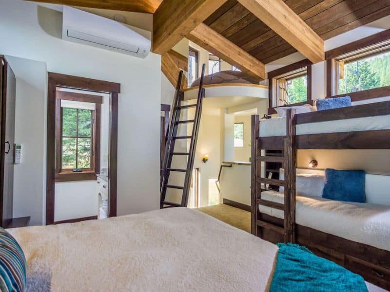 A Whitefish MT rental with a bedroom featuring bunk beds and a ladder leading to a small loft.