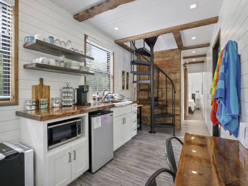 A small kitchen in a container cabin with a spiral staircase.