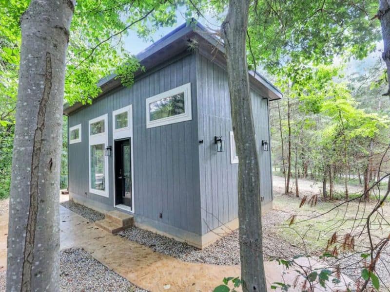 Exterior of The Nook, a modern container cabin in Hocking Hills, surrounded by trees.
