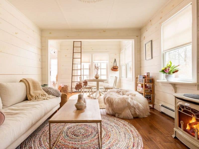 Charming dining and living space inside a cozy cabin in the Catskills, featuring a rustic ladder, round table, and a mix of modern and traditional decor.