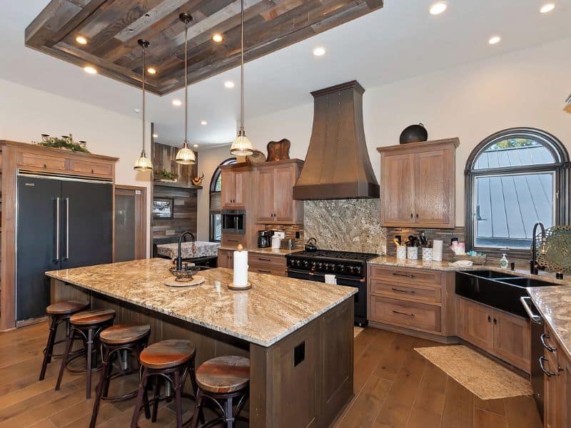Modern kitchen in a Big Bear cabin on the lake, complete with bar stools, granite countertops, and a rustic range hood.