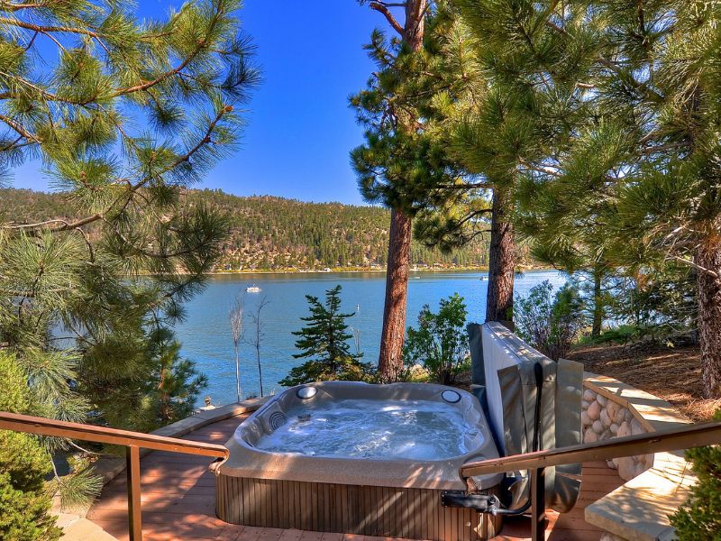 Hot tub on the deck of a Big Bear rental with views of the lake and surrounding pine trees.