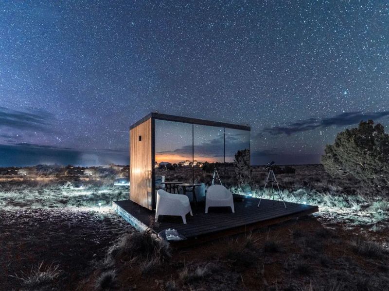 Mirrored cabin "Grand Canyon Stargazer" under a star-filled sky. The cabin's reflective surface blends with the night.