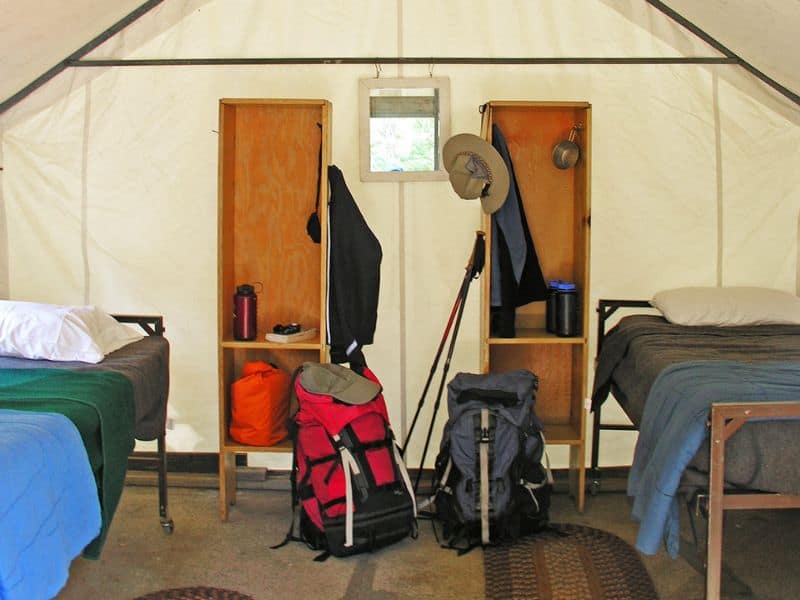 Inside a Yosemite High Sierra Camp tent with beds and hiking gear, an adventurous glamping experience in Yosemite.