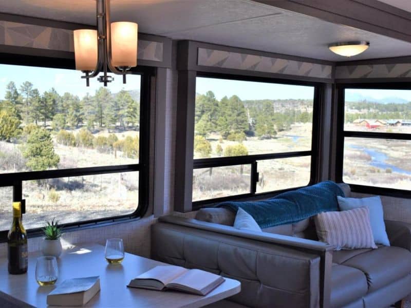 Comfortable sitting area inside an RV at Grand Canyon RV Glamping in Williams with large windows, complemented by a bottle of wine on the table.